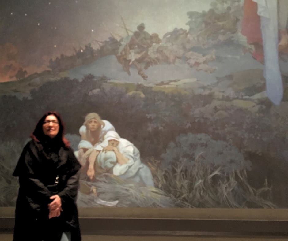 Woman contemplating Mucha's monumental battle murals in Prague that tell stories of cultural resilience and survival